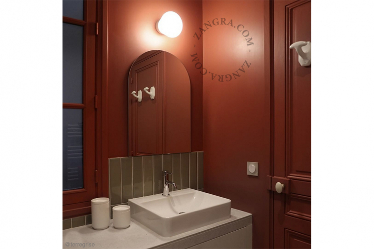 White porcelain wall light with glass globe for bathroom or outdoor use.