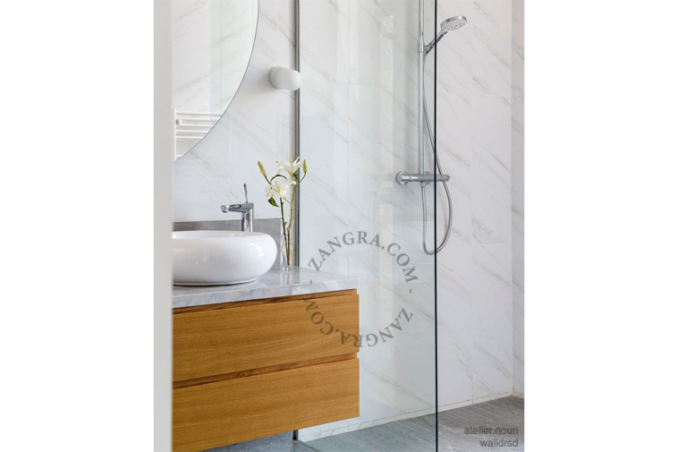 White porcelain wall light with glass globe for bathroom or outdoor use.