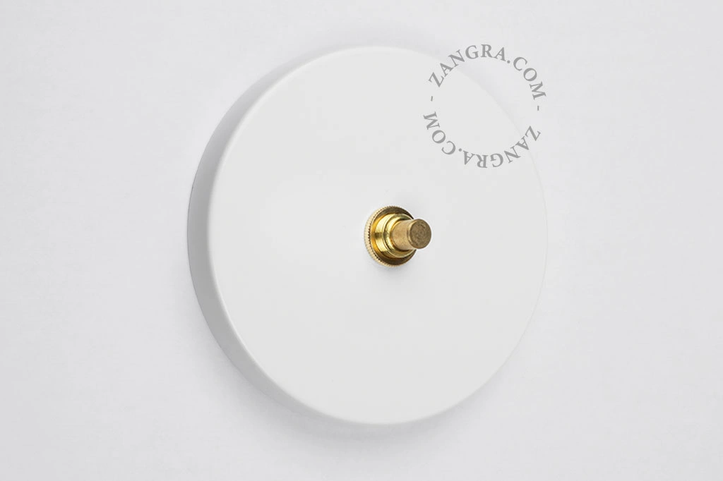 witte schakelaar met goudkleurige drukknop