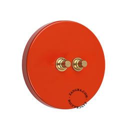 bouton-poussoir en laiton brut sur une plaquette de finition rouge