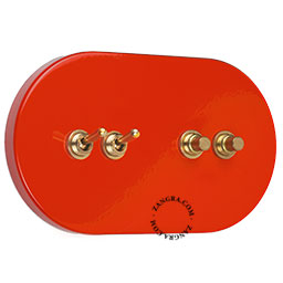 interrupteur arrondi avec 2 boutons-poussoirs et 2 leviers dorés sur une plaquette de finition rouge
