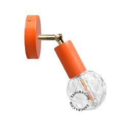 Orange adjustable wall light with brass arm.