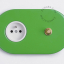 Green outlet & switch with raw brass pushbutton.
