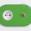 Green outlet & switch with raw brass toggle.