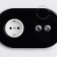 Black wall outlet with double switch with nickel-plated pushbuttons.