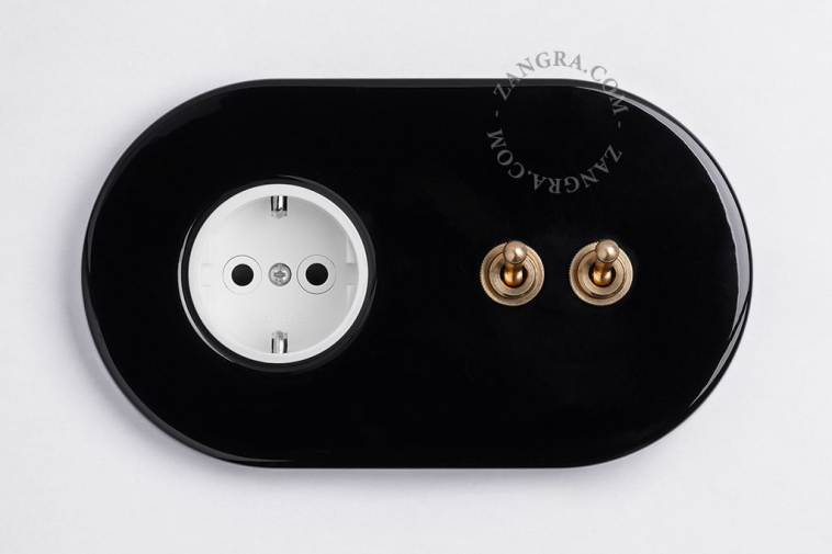 Black flush mount outlet & switch with double raw brass toggle.