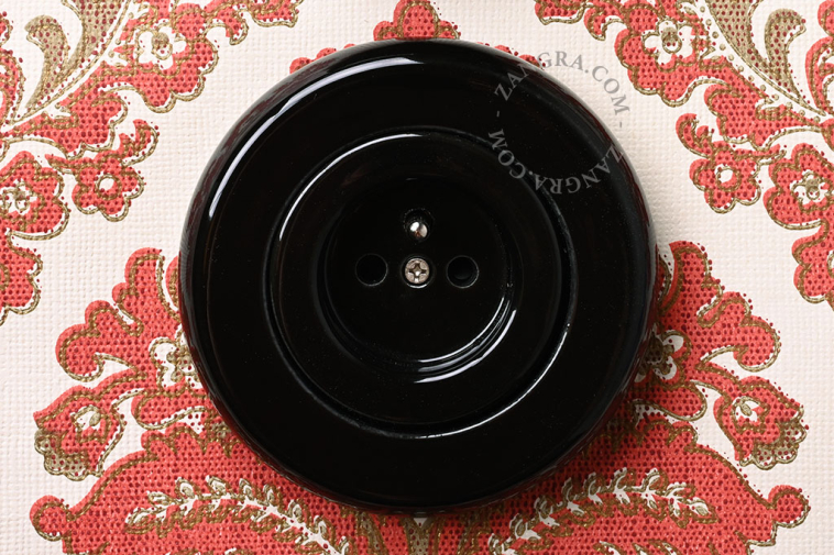 Unterputzsteckdose aus schwarzem Porzellan.