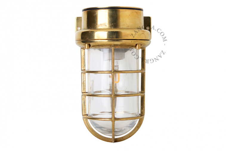 Marine-inspired brass wall light with transparent glass.
