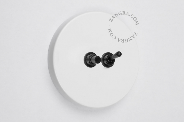 White round light switch with black pushbutton and toggle