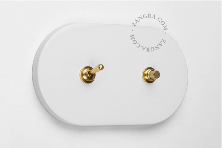 White light switch with brass toggle and brass pushbutton.