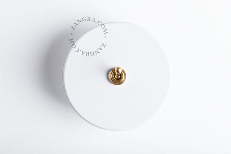 Brass toggle round white light switch.