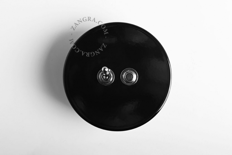 Round black switch with one nickel-plated toggle and one pushbutton.
