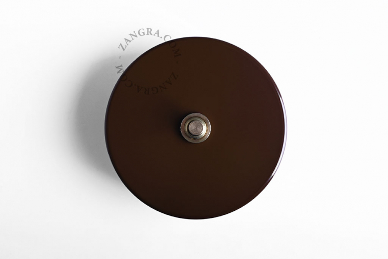 Round brown brass pushbutton switch.