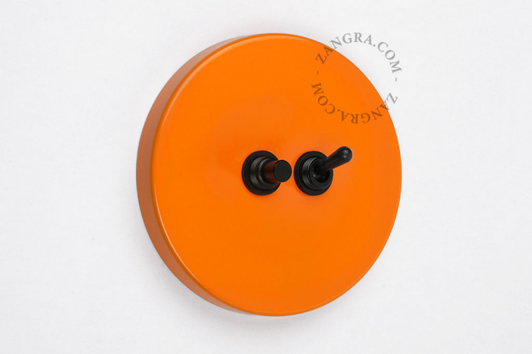 Oranje schakelaar met een zwarte drukknop en tuimelschakelaar.