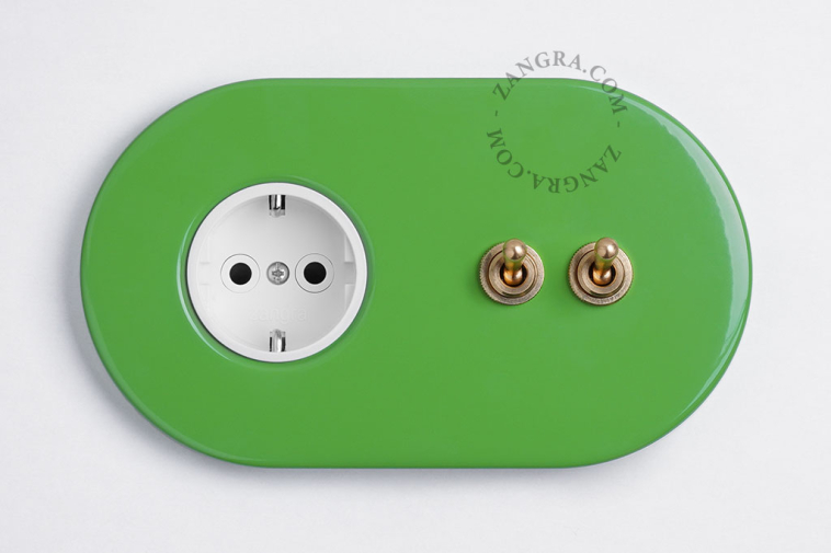 Green flush mount outlet & switch with raw brass double lever.