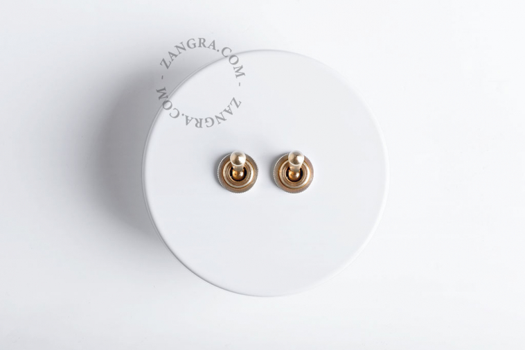 Round white switch with double raw brass toggles