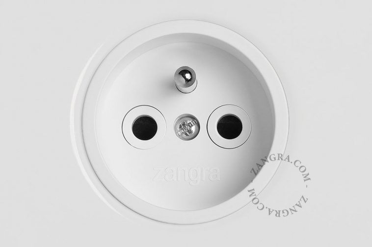 White flush mount outlet & switch with a raw brass pushbutton.