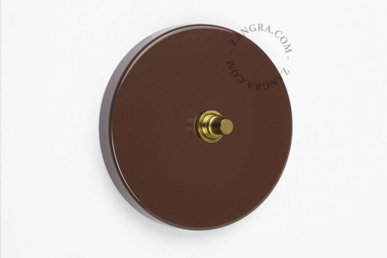 Round brown brass pushbutton switch.