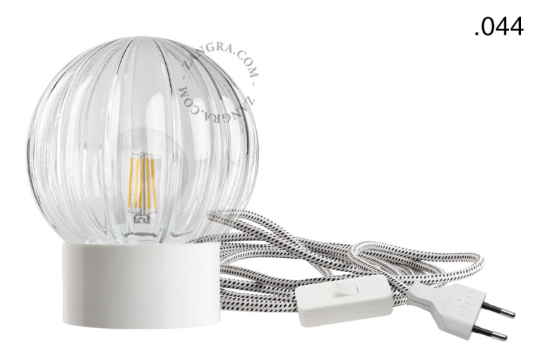 Bordslampa i vitt porslin med glasskärm och strömbrytare.