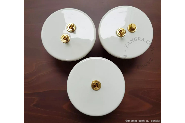White porcelain switch with double toggle in brass.