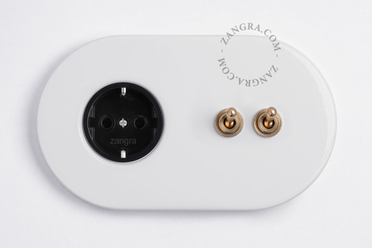 White flush mount outlet & switch with double raw brass toggle.