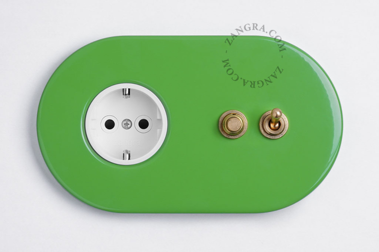 Green outlet & switch with raw brass toggle & pushbutton.