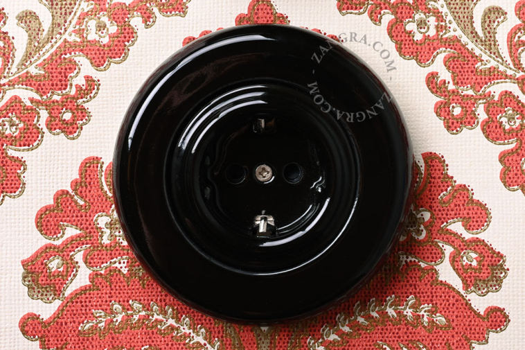 Unterputzsteckdose aus schwarzem Porzellan.