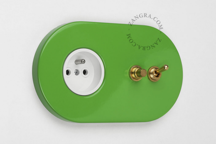 Green outlet & switch with raw brass toggle & pushbutton.